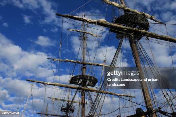 old boat and masts under blue and cloudy sky - bateau à voile stockfoto's en -beelden