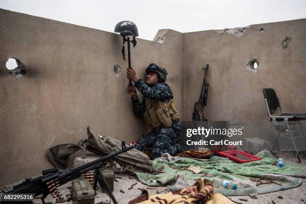 An Iraqi federal policeman uses a helmet on a stick to try and draw fire from an Islamic State sniper in an attempt to make him reveal his position...