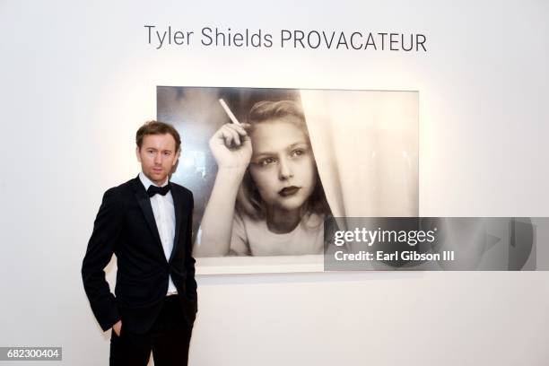 Photographer Tyler Shields poses next to one of his photos at his "Provocateur" Opening at Leica Store and Gallery Los Angeles on May 11, 2017 in Los...