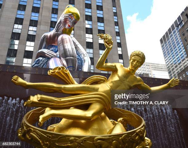 The golden statue of Prometheus sits in front of the public art exhibition of a 45-foot tall inflatable nylon sculpture depicting a seated ballerina...