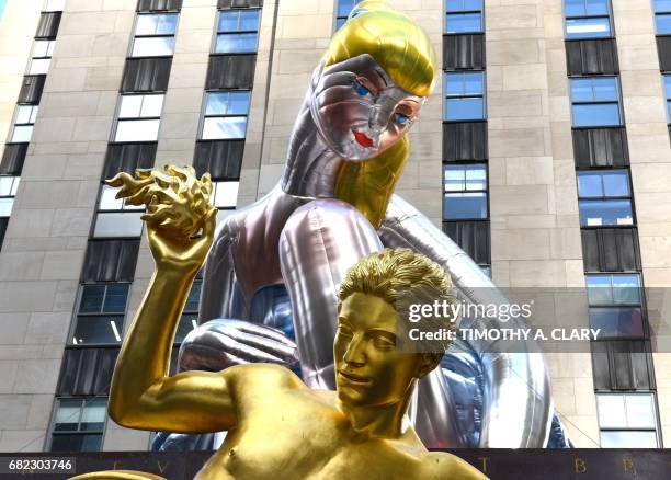 The golden statue of Prometheus sits in front of the public art exhibition of a 45-foot tall inflatable nylon sculpture depicting a seated ballerina...