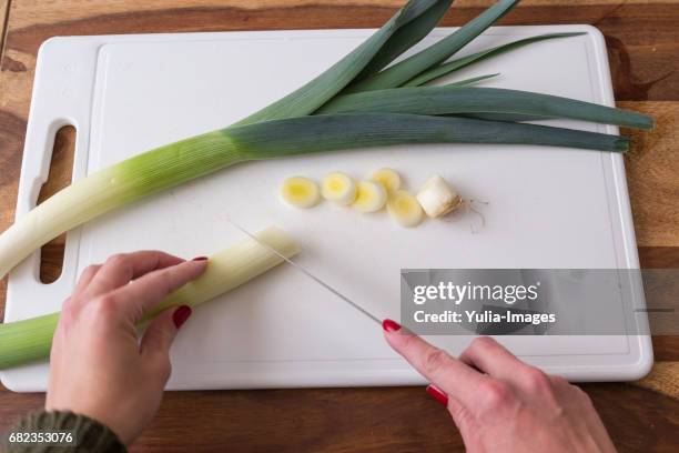 person cutting leeks on cutting board - tabla de cortar fotografías e imágenes de stock