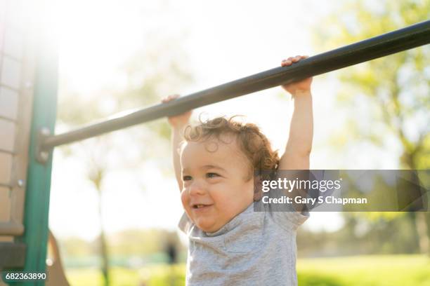 male toddler exercising on a playground pullup bar. - boys in pullups stockfoto's en -beelden