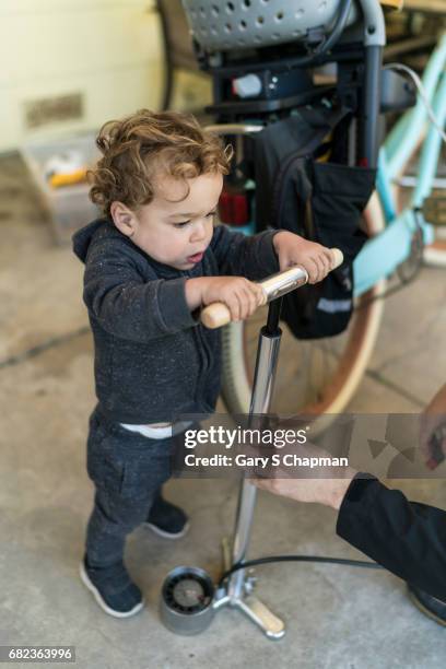 toddler helps pump up bike tire. - luftpumpe stock-fotos und bilder