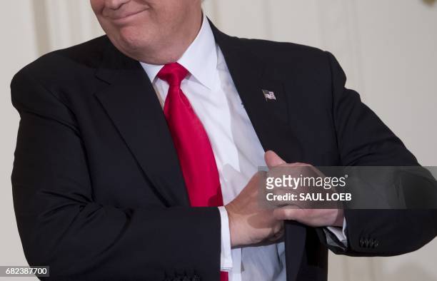 President Donald Trump puts away his speaking notes after speaking during a Mother's Day event hosted by First Lady Melania Trump for military...