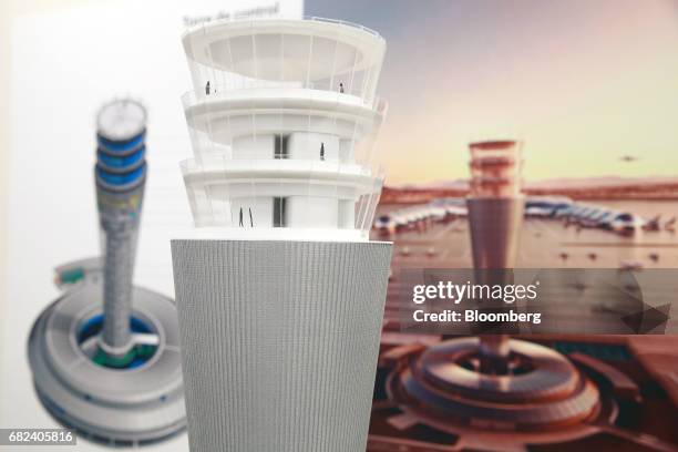 Model replica of the control tower stands on display in front of digital renderings at an exhibition room on the grounds of the New International...