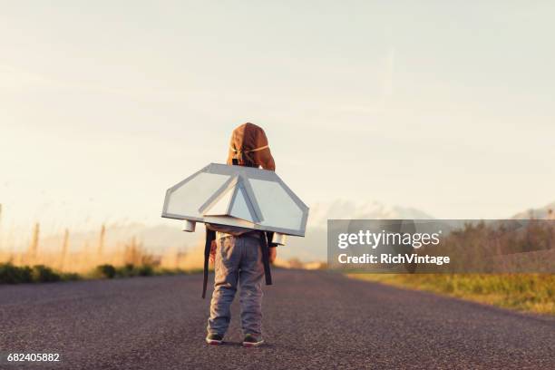 young boy mit jet pack schaut in den himmel - flugzeugflügel stock-fotos und bilder