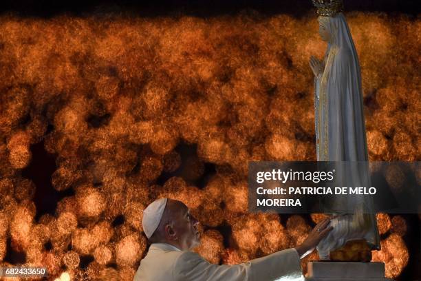 Pope Francis touches the figure representing Our Lady of Fatima during his visit to the Chapel of the Apparitions at the Fatima shrine, in Fatima on...