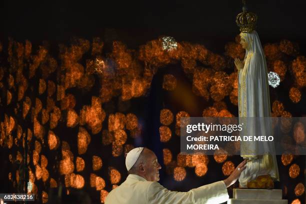 Pope Francis touches a figure representing Our Lady of Fatima during the Blessing for the Candles from the Chapel of the Apparitions, in Fatima on...