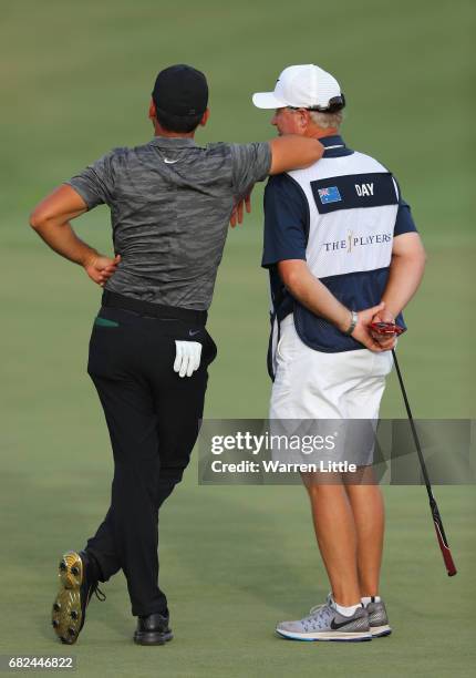Jason Day of Australia leans on caddie Colin Swatton on the 18th green during the second round of THE PLAYERS Championship at the Stadium course at...