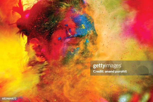 a young girl enjoying shower of colours during holi festival, india - holi festival and indian person foto e immagini stock