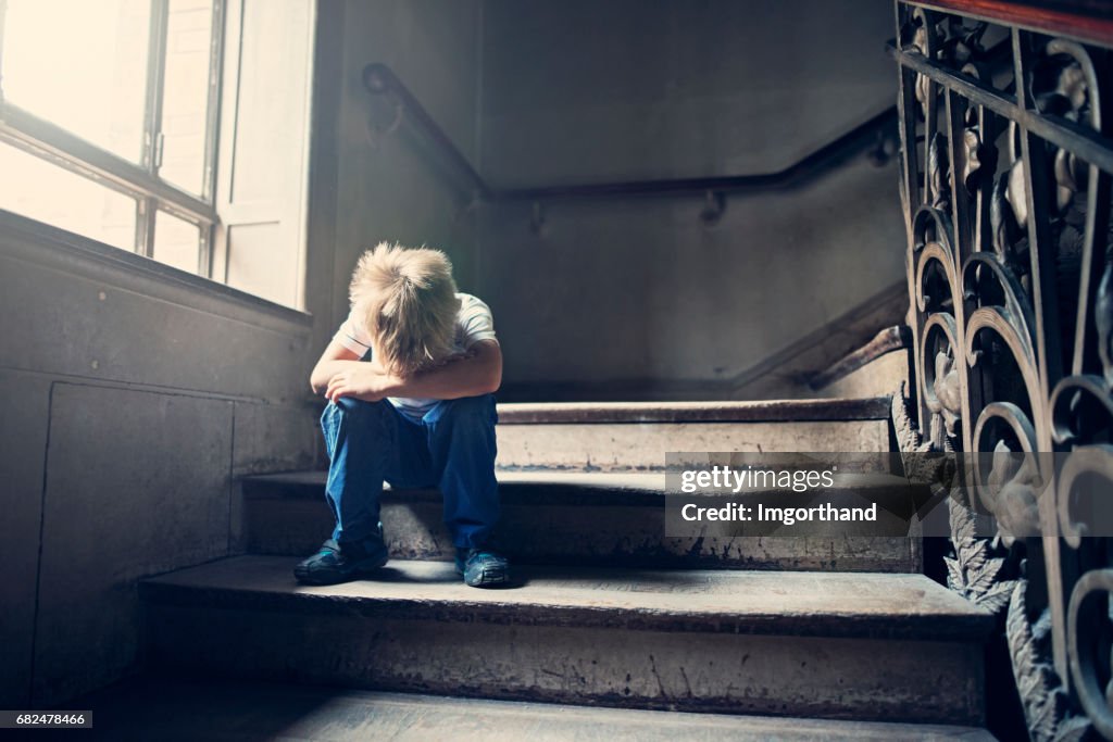 Little child crying on an old staircase