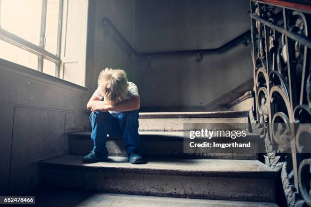 little child crying on an old staircase - childhood poverty stock pictures, royalty-free photos & images