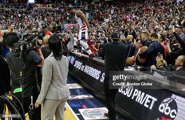 Washington Wizards guard John Wall celebrates on top of the officials table after time ran out on the Celtics and Wall's three pointer with 0:03 held...