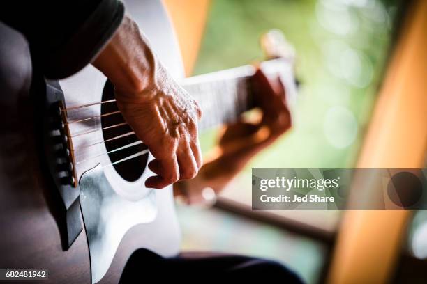 strumming an acoustic guitar - plucking an instrument foto e immagini stock