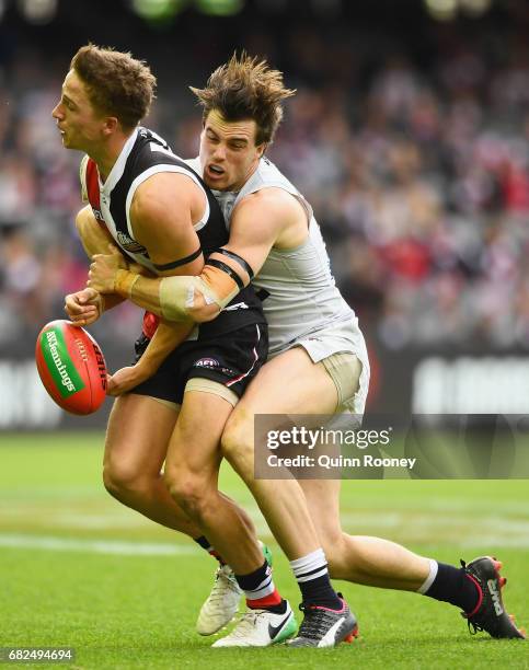 Jack Billings of the Saints handballs whilst being tackled by Lachie Plowman of the Blues during the round eight AFL match between the St Kilda...