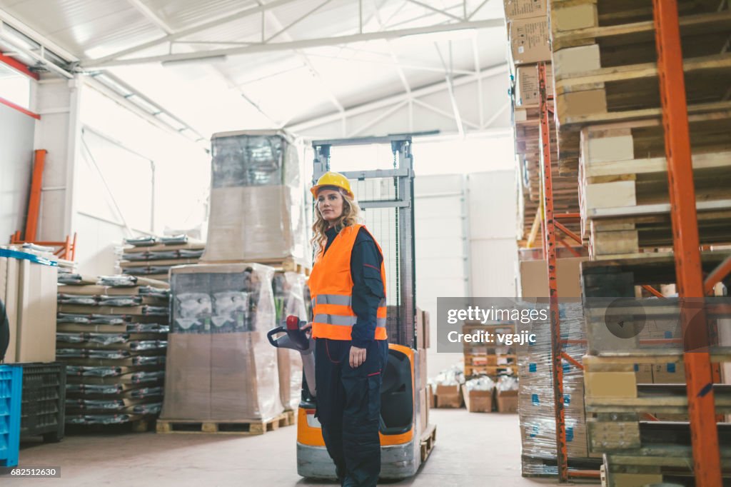 Female worker pulling pallet jack in warehouse