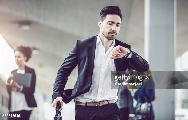 geschäftsmann auf die uhr sehen - businessman after work stock-fotos und bilder