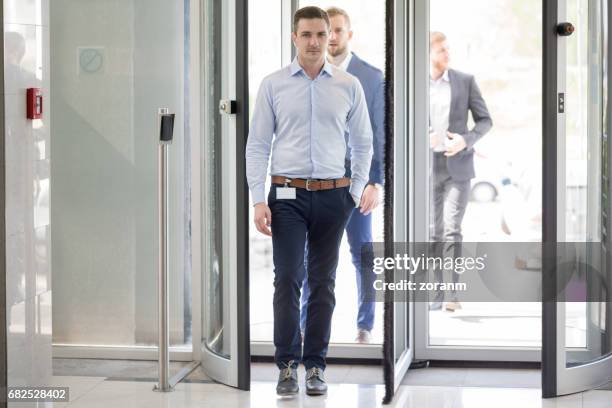 businessman entering office building - revolving door stock pictures, royalty-free photos & images