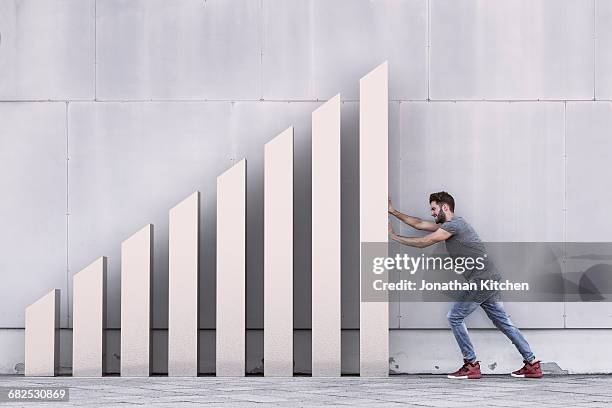 a silver bar chart with man pushing - pousser à plusieurs photos et images de collection