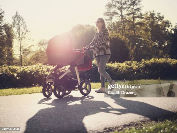 young mother and her baby in baby carriage - mother stroller stock pictures, royalty-free photos & images