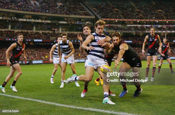 Jake Kolodjashnij of the Cats kicks the ball away from Jobe Watson of the Bombers during the round eight AFL match between the Essendon Bombers and...
