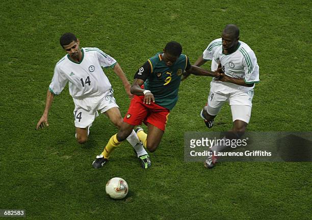 Samuel Eto'o of Cameroon takes the ball past Abdulaziz al Khathran and Abdullah Sulaiman Zubromawi of Saudi Arabia during the FIFA World Cup Finals...