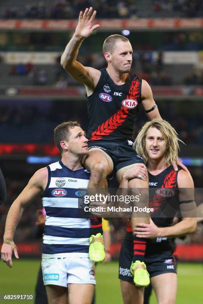 James Kelly of the Bombers celebrates the win on top of former teammate Joel Selwood of the Cats and teammate Dyson Heppell in his 300th match during...