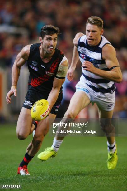 David Myers of the Bombers runs with the ball away from Mark Blicavs of the Cats during the round eight AFL match between the Essendon Bombers and...