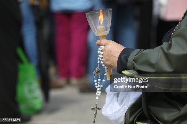 Pilgrim holds a candle and a rosary as Pope Francis celebrates a mass on the centenary of the apparition of Virgin Mary, at the Shrine of Our Lady of...