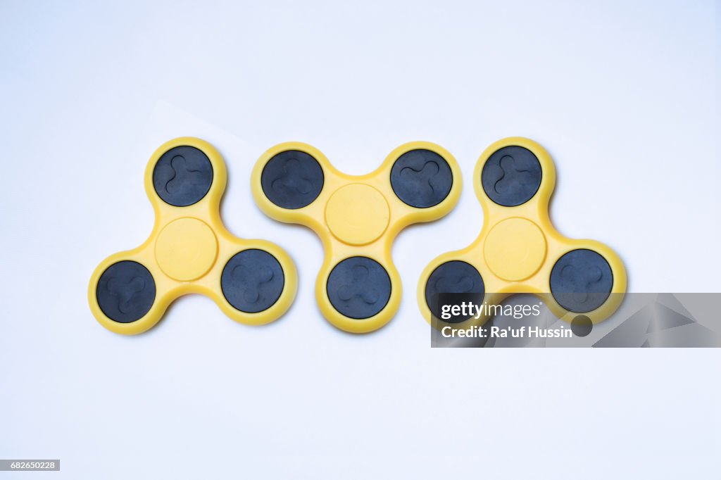 Three yellow fidget spinner stress relieving toy on white background