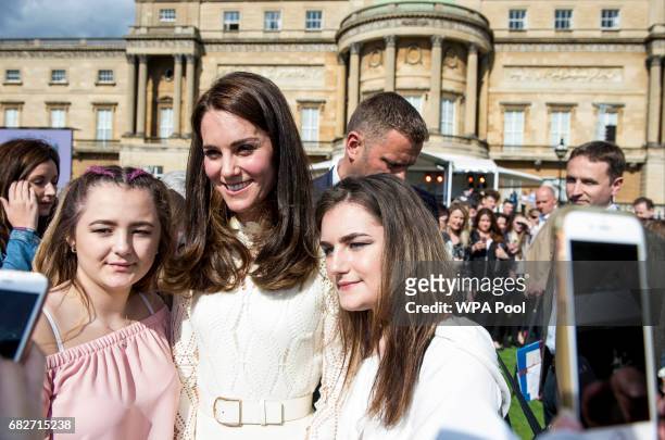 Catherine, Duchess of Cambridge poses for a picture with guests as they host a tea party in the grounds of Buckingham Palace to honour the children...