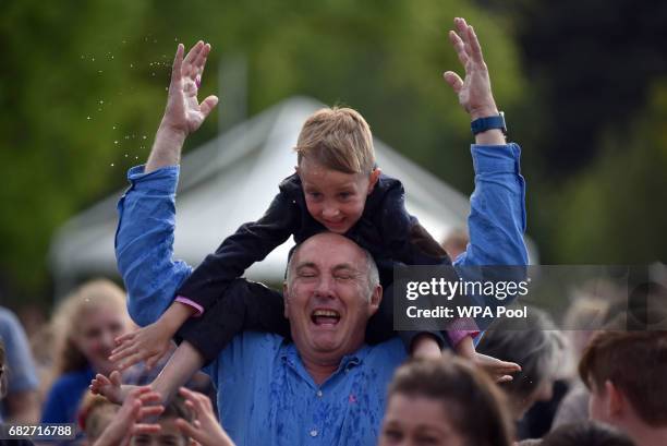 Man and a child are hit by a water balloon fired by a member of royal family as they host a tea party in the grounds of Buckingham Palace to honour...