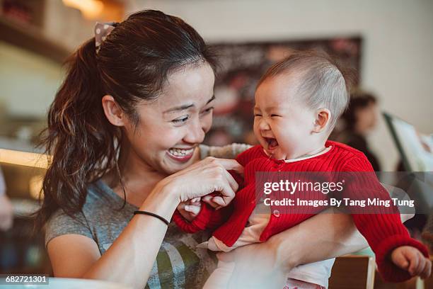 mom playing with baby joyfully in restaurant - chinese ethnicity stock pictures, royalty-free photos & images