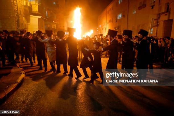 Ultra-Orthodox Jewish men dance as they light a giant oil fire in the Mea Shearim neighborhood of Jerusalem on May 13, 2017 during the celebration of...