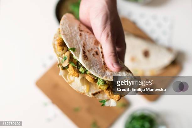 human hand holding homemade chicken taco - wrap sandwich stock-fotos und bilder