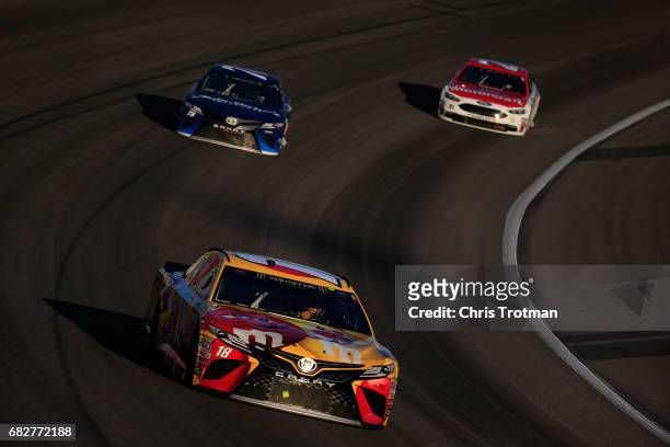 Kyle Busch, driver of the M&M's Red Nose Toyota, leads Martin Truex Jr., driver of the Auto-Owners Insurance Toyota, and Ryan Blaney, driver of the...