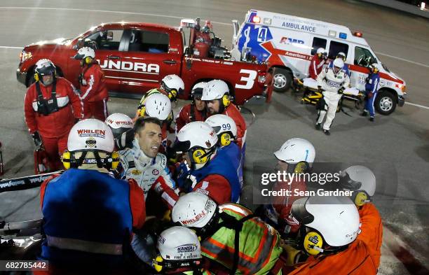 Safety crew workers place Aric Almirola, driver of the Smithfield Ford, on a stretcher after cutting off the roof of his car after a crash during the...