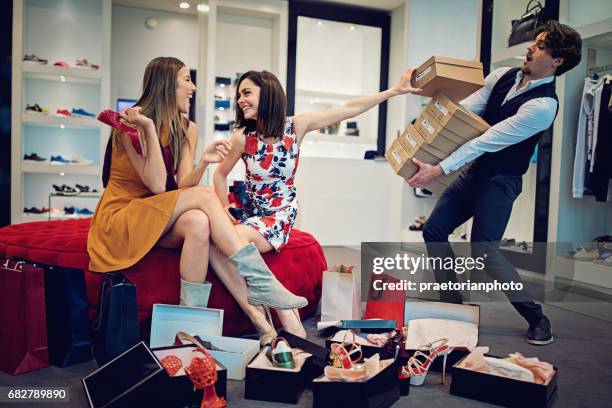 shopping girls are choosing shoes and asking from salesman for more - shoe seller imagens e fotografias de stock