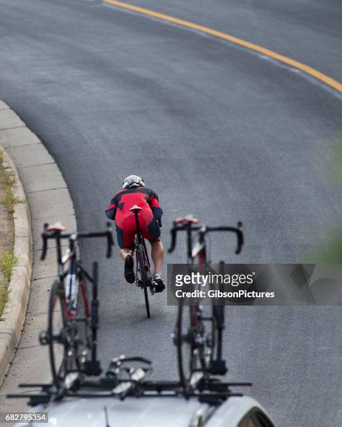 a man gets into an aerodynamic position while riding a downhill in a time trial during a profession road bike race. - prova de ciclismo imagens e fotografias de stock
