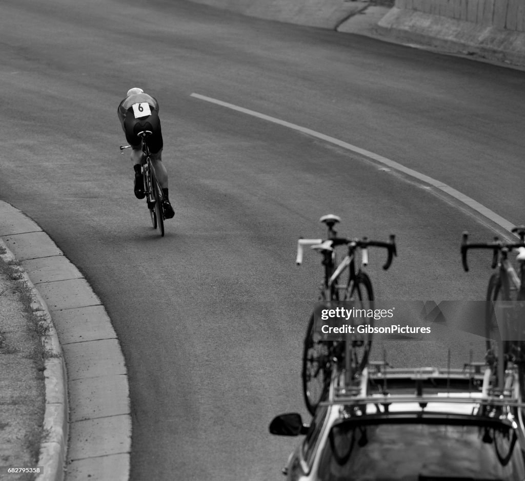 Um homem entra em uma posição aerodinâmica ao montar uma descida a um tempo experimental durante uma corrida de bicicleta de estrada de profissão.