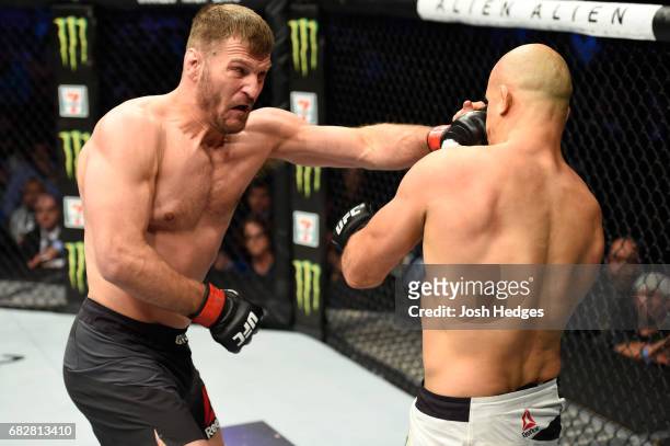Stipe Miocic punches Junior Dos Santos in their UFC heavyweight championship fight during the UFC 211 event at the American Airlines Center on May...
