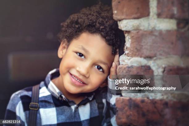 portrait of a four year old boy leaning against some bricks in a city - 5 year stock pictures, royalty-free photos & images