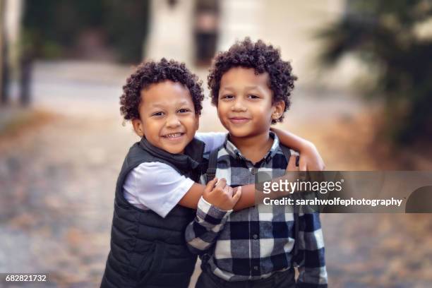 handsome l twin brothers hugging and standing in an urban scene - twin stock pictures, royalty-free photos & images