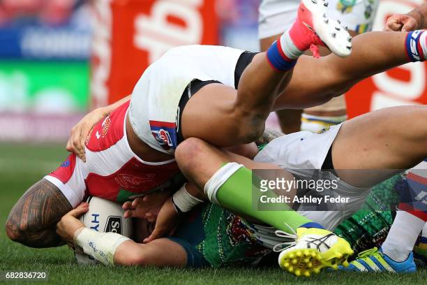 Peter Mata'Utia of the Knights scores a try while being tackled by the Raiders defenced during the round 10 NRL match between the Newcastle Knights...