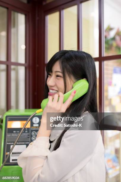 happy young woman talking over the phone in telephone box - pay phone stock pictures, royalty-free photos & images
