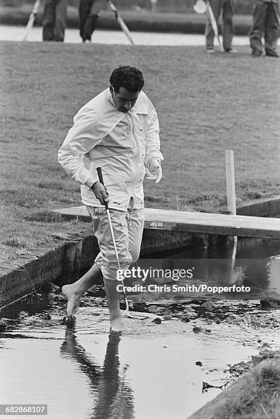 Scottish golfer Sam Torrance pictured bare footed as he paddles in a stream to look for his ball during play for Team Europe to win the 1985 Ryder...