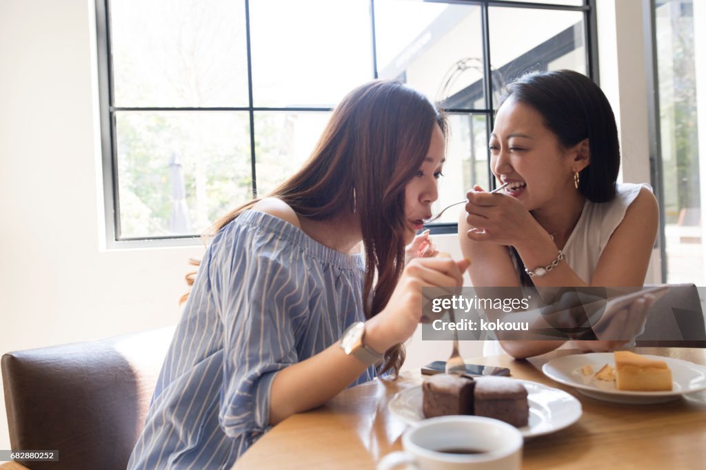 The girls eat cakes at the cafe.