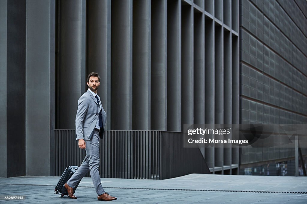 Confident businessman with bag against building
