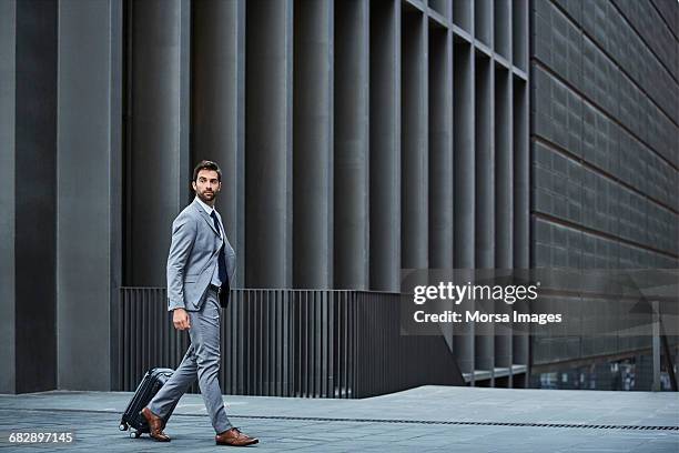 confident businessman with bag against building - 歩く ストックフォトと画像